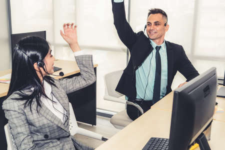 Business people wearing headset celebrate working in officeの写真素材