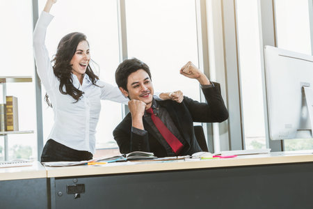 Two happy business people celebrate at office