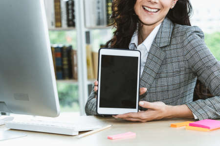 Empty tablet computer screen shown by woman in office for product , website and mobile app presentation.の写真素材
