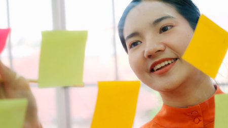 Business people work on project planning board in office and having conversation with coworker...