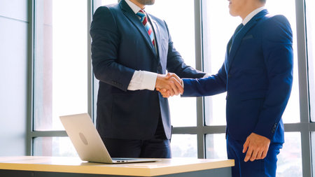 Business people handshake in corporate office showing professional agreement on a financial deal...