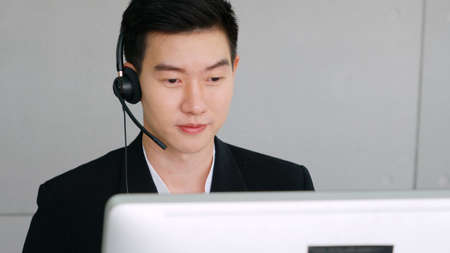 Business people wearing headset working in office to support remote customer or colleague. Call center, telemarketing, customer support agent provide service on telephone video conference call.の写真素材