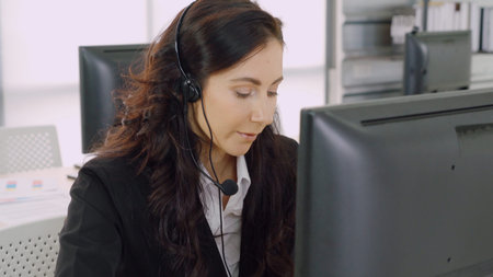 Business people wearing headset working in office to support remote customer or colleague. Call center, telemarketing, customer support agent provide service on telephone video conference call.の写真素材