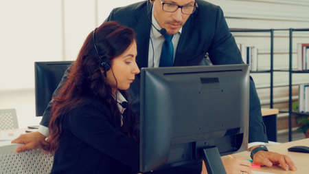Business people wearing headset working in office to support remote customer or colleague. Call center, telemarketing, customer support agent provide service on telephone video conference call.の写真素材