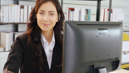 Business people wearing headset working in office to support remote customer or colleague. Call center, telemarketing, customer support agent provide service on telephone video conference call.の写真素材