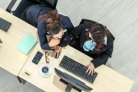 Business people wearing headset from top view in office working with computer to support remote customer or colleague. Call center, telemarketing agent service on telephone or video conference call.の写真素材