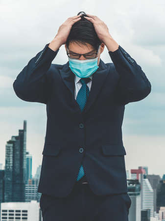Unhappy lost business man with face mask protect from Coronavirus or Covid-19 suffers economic recession trouble. Concept of unemployment problem crisis caused by pandemic of Coronavirus Covid-19.の写真素材