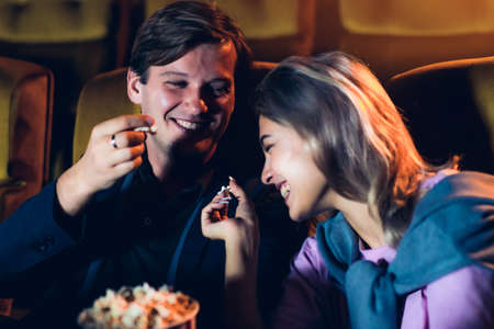 Caucasian lover enjoying to watch movie and eating popcorn together in the cinemaの写真素材