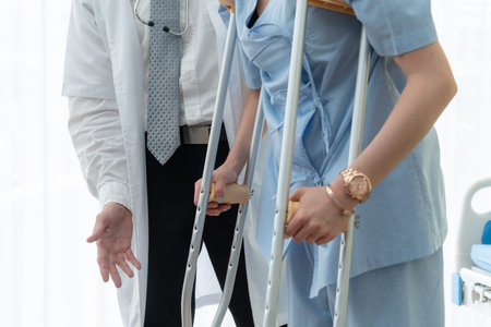 Doctor takes care of patient in crutch at hospital. Physical therapist and leg injury recovery...