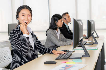 Business people wearing headset working in office to support remote customer or colleague. Call center, telemarketing, customer support agent provide service on telephone video conference call.の写真素材