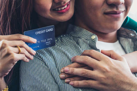 Young couple use credit card for online shopping on internet website at home. Number on the credit card is mock up. No personal information shown on the credit card. Online business shopping concept.の写真素材