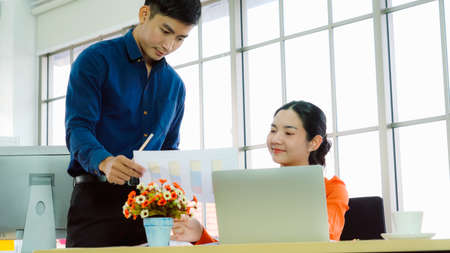 Two business people talk project strategy at office meeting room. Businessman discuss project planning with colleague at modern workplace while having conversation and advice on financial data report.の写真素材