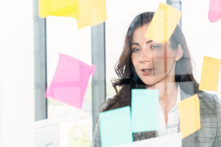 Business people work on project planning board in office and having conversation with coworker...
