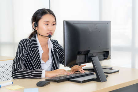 Business people wearing headset working in office to support remote customer or colleague. Call center, telemarketing, customer support agent provide service on telephone video conference call.の写真素材