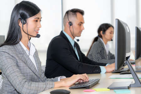 Business people wearing headset working in office to support remote customer or colleague. Call center, telemarketing, customer support agent provide service on telephone video conference call.の写真素材