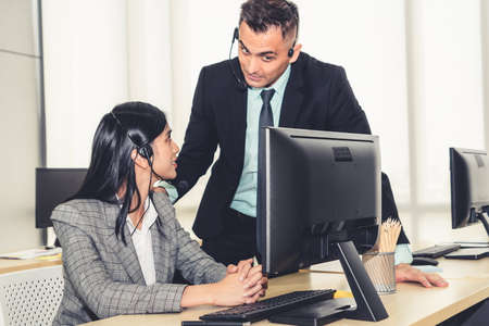 Business people wearing headset working in office to support remote customer or colleague. Call center, telemarketing, customer support agent provide service on telephone video conference call.の写真素材