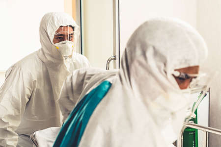 Emergency medic and doctor moving patient to emergency room in hospital . Doctor wears protective suit and face mask in concept of coronavirus and covid 19 protection and quarantine .の写真素材