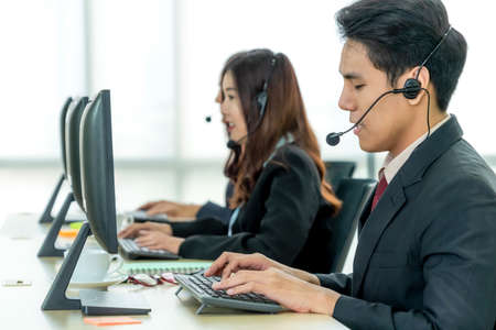 Business people wearing headset working in office to support remote customer or colleague. Call center, telemarketing, customer support agent provide service on telephone video conference call.の写真素材