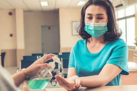 Receptionist and guest wearing face mask at front desk while having conversation in office or hospital . Covid 19 and coronavirus infection protection and protective policy concept .の写真素材