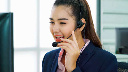 Business people wearing headset working in office to support remote customer or colleague. Call center, telemarketing, customer support agent provide service on telephone video conference call.の写真素材