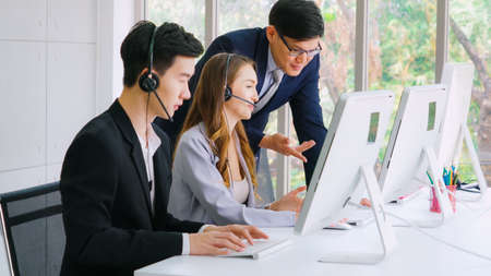Business people wearing headset working in office to support remote customer or colleague. Call center, telemarketing, customer support agent provide service on telephone video conference call.の写真素材
