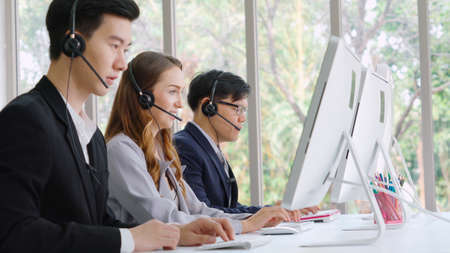Business people wearing headset working in office to support remote customer or colleague. Call center, telemarketing, customer support agent provide service on telephone video conference call.の写真素材