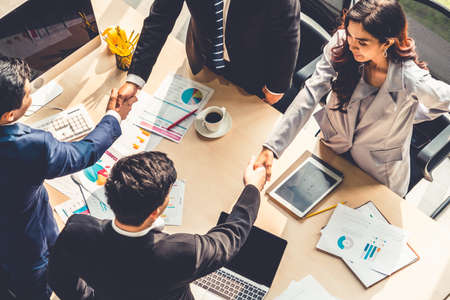 Group business people handshake at meeting table in office together with confident shot from top view . Young businessman and businesswoman workers express agreement of investment deal.の写真素材