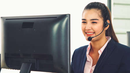 Business people wearing headset working in office to support remote customer or colleague. Call center, telemarketing, customer support agent provide service on telephone video conference call.の写真素材