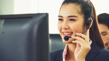 Business people wearing headset working in office to support remote customer or colleague. Call center, telemarketing, customer support agent provide service on telephone video conference call.の写真素材