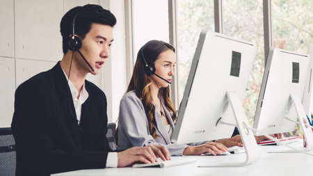 Business people wearing headset working in office to support remote customer or colleague. Call center, telemarketing, customer support agent provide service on telephone video conference call.の写真素材
