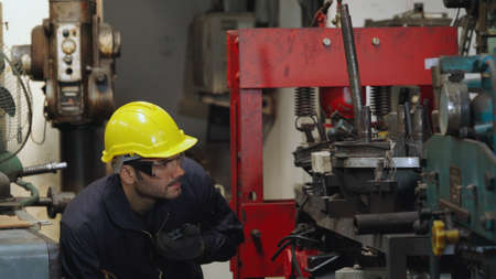 Factory worker talking on portable radio while inspecting machinery parts . Industrial and engineering team communication concept .の写真素材