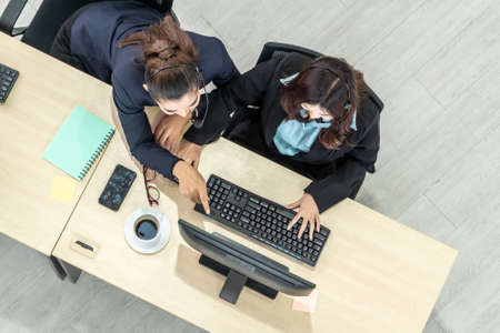 Business people wearing headset from top view in office working with computer to support remote customer or colleague. Call center, telemarketing agent service on telephone or video conference call.の写真素材