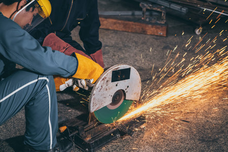 Professional mechanic man is cutting steel metal with rotating carbon blade cutter. Steel industry...