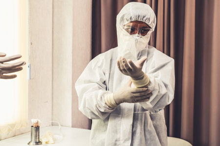 Doctor in PPE suit , face mask and face shield in hospital ward protected from Coronavirus and...