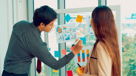 Business people work on project planning board in office and having conversation with coworker...