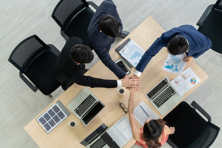 Happy business people celebrate teamwork success together with joy at office table shot from top...
