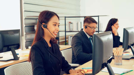 Business people wearing headset working in office to support remote customer or colleague. Call center, telemarketing, customer support agent provide service on telephone video conference call.の写真素材