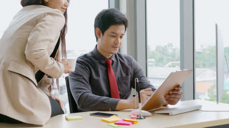 Two business people talk project strategy at office meeting room. Businessman discuss project planning with colleague at modern workplace while having conversation and advice on financial data report.の写真素材