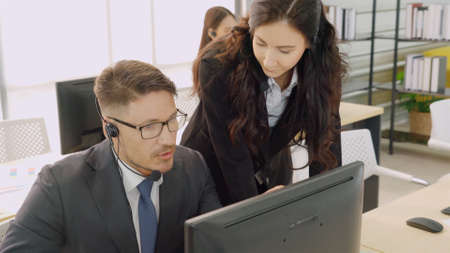 Business people wearing headset working in office to support remote customer or colleague. Call center, telemarketing, customer support agent provide service on telephone video conference call.の写真素材