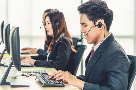 Business people wearing headset working in office to support remote customer or colleague. Call center, telemarketing, customer support agent provide service on telephone video conference call.の写真素材