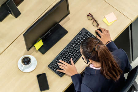 Business people wearing headset from top view in office working with computer to support remote customer or colleague. Call center, telemarketing agent service on telephone or video conference call.の写真素材