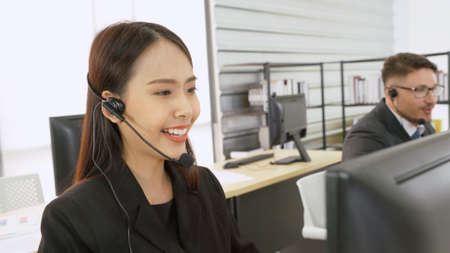 Business people wearing headset working in office to support remote customer or colleague. Call center, telemarketing, customer support agent provide service on telephone video conference call.の写真素材