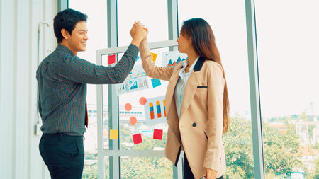 Business people work on project planning board in office and having conversation with coworker friend to analyze project development . They use sticky notes posted on glass wall to make it organized .の写真素材