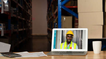 Warehouse staff talking on video call at computer screen in storage warehouse . Online software technology connects people working in logistic factory by virtual conference call on internet network .の写真素材