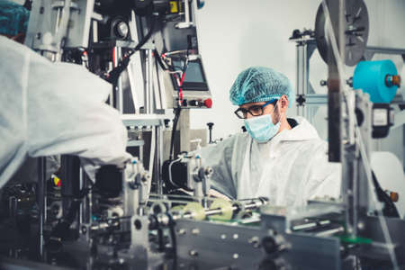 Production line worker with face mask working in electronic factory . Concept of protective action and quarantine to stop spreading of Coronavirus Disease 2019 or COVID-19 .の写真素材