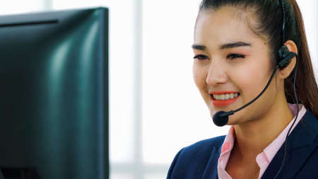 Business people wearing headset working in office to support remote customer or colleague. Call center, telemarketing, customer support agent provide service on telephone video conference call.の写真素材
