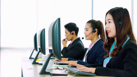 Business people wearing headset working in office to support remote customer or colleague. Call center, telemarketing, customer support agent provide service on telephone video conference call.の写真素材