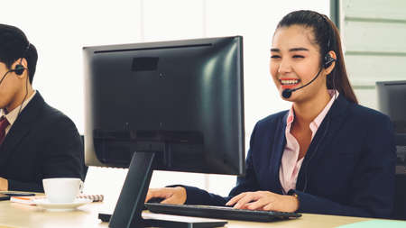 Business people wearing headset working in office to support remote customer or colleague. Call center, telemarketing, customer support agent provide service on telephone video conference call.の写真素材
