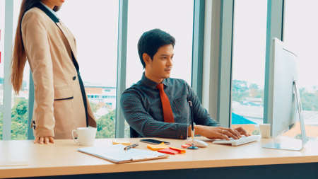 Two business people talk project strategy at office meeting room. Businessman discuss project planning with colleague at modern workplace while having conversation and advice on financial data report.の写真素材