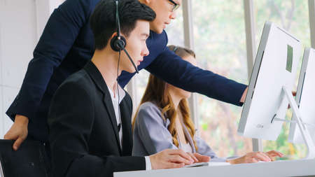 Business people wearing headset working in office to support remote customer or colleague. Call center, telemarketing, customer support agent provide service on telephone video conference call.の写真素材